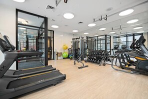 Une salle de sport moderne équipée de tapis de course, d’haltères et de ballons d’exercice.