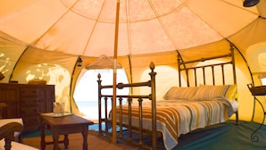 A tent with a bed, a dresser, and a table. - Wild Lotus Glamping (Bequia Island)