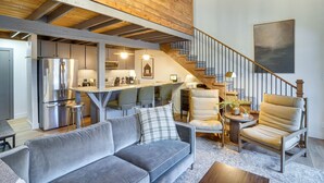 A spacious living area with a grey sofa, a wooden ceiling, a staircase, and a kitchen in the background. - Mountain-View Condo in Brian Head w/ Private Sauna (Brian Head)
