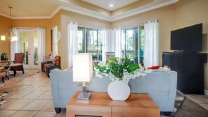 A living room with a sofa, a TV, and a wooden coffee table with a vase of flowers.