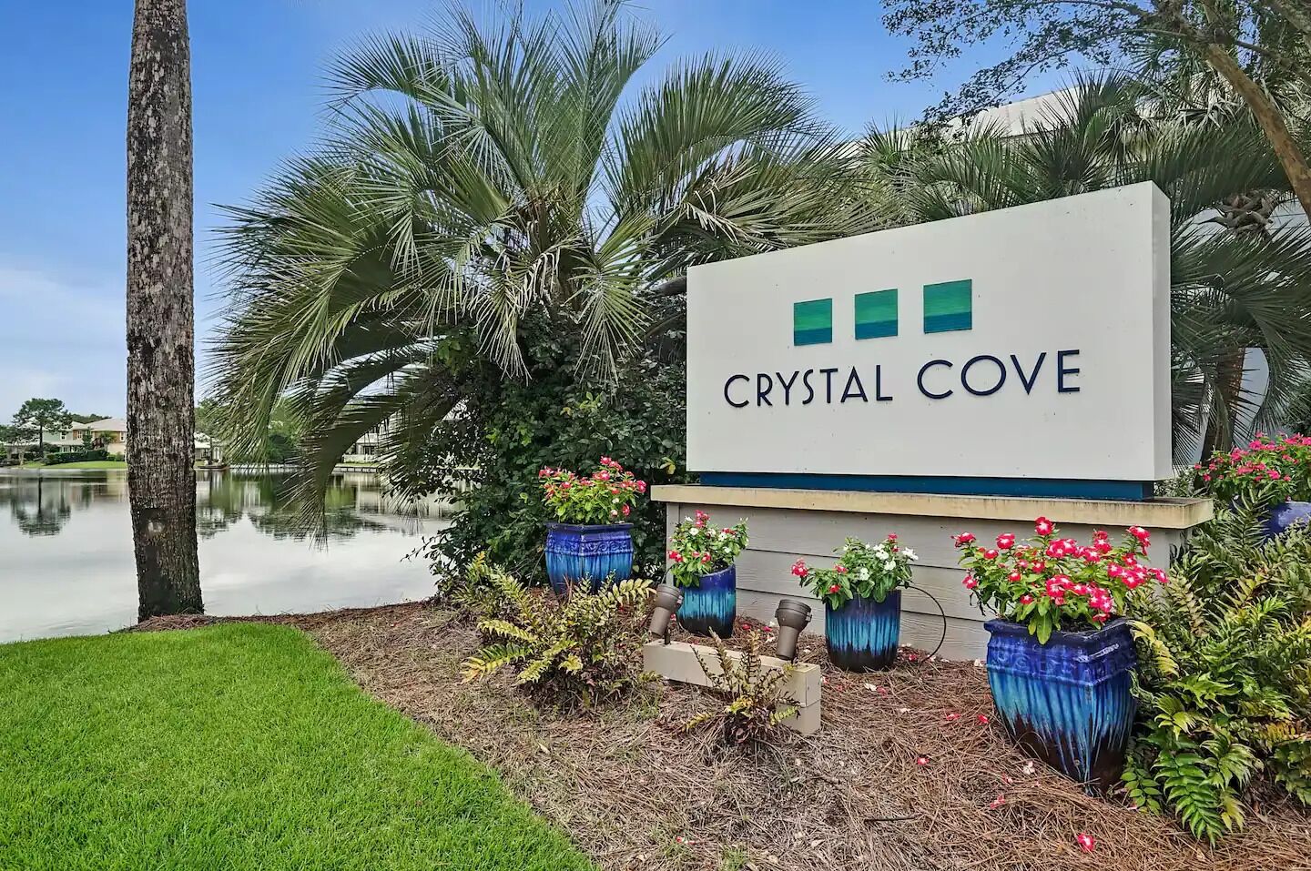 A sign for 'Crystal Cove' with a lake and palm trees in the background.