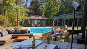 Un patio exterior con piscina, mobiliario y una mesa dispuesta para comer.