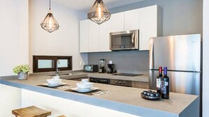 Een moderne keuken met een groot kookeiland, roestvrijstalen apparatuur en hanglampen.