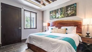 Een moderne slaapkamer met een groot bed, een houten hoofdbord en kunst aan de muur.
