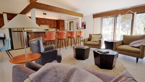 Una sala de estar moderna con un sofá, dos sillones, una mesa de centro y un comedor con barra.