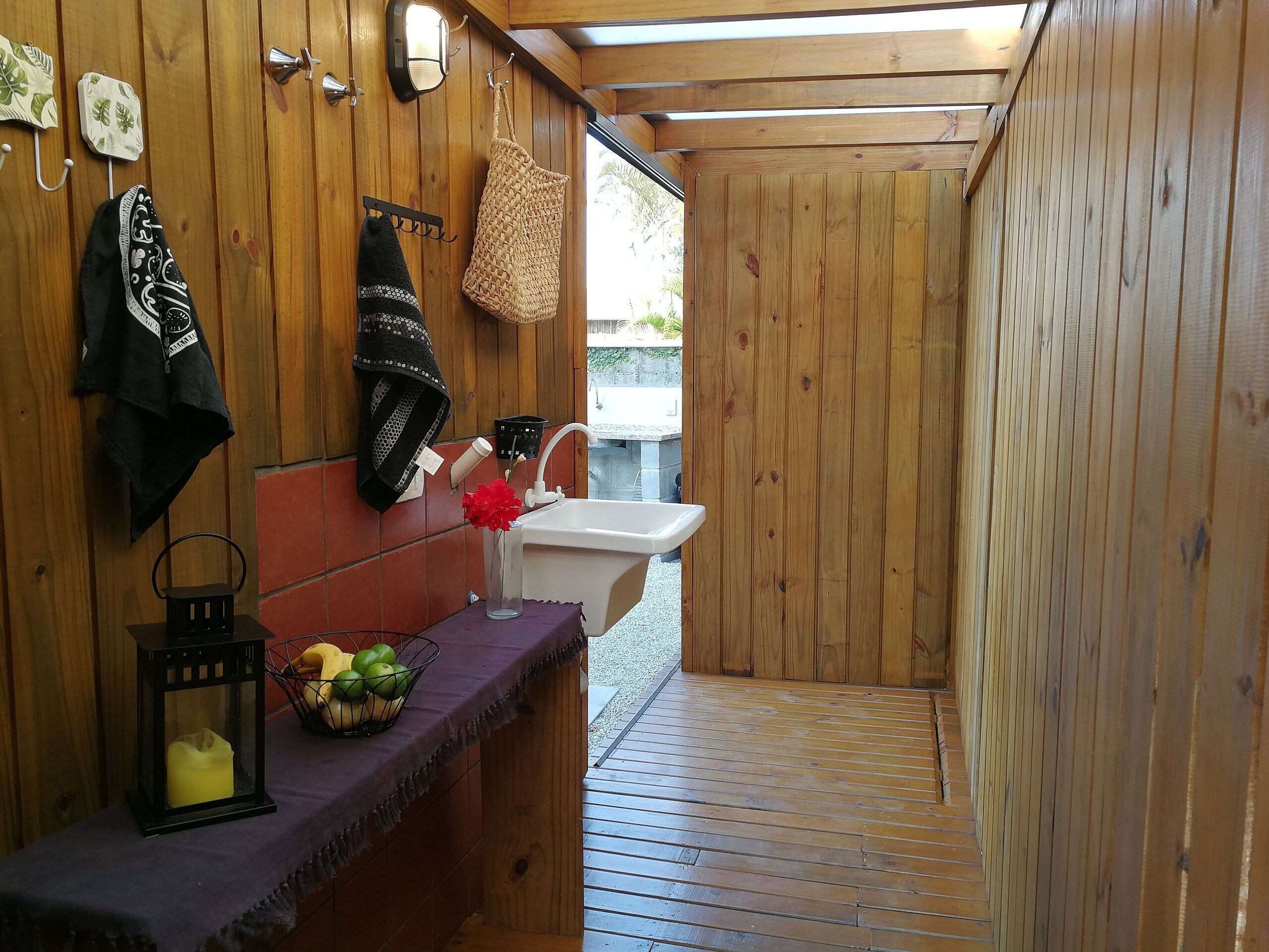 A wooden interior with a sink, a mirror, and a towel rack.