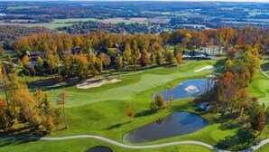 Una vista aerea di un campo da golf con diverse buche, stagni e un club house.
