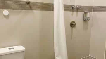 A bathroom with a toilet, a shower with a curved showerhead, and a tiled floor.