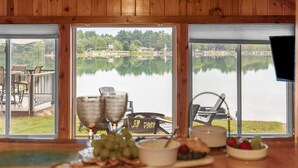 Ein Holzinterieur mit Essbereich mit Seeblick, inklusive Tisch mit Speisen und an der Wand montiertem Fernseher.
