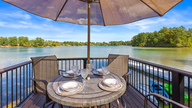 Eine Terrasse mit Esstisch, mit Blick auf einen See.