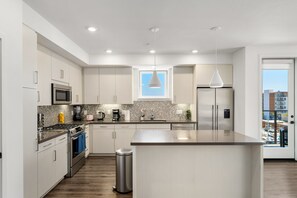 A modern kitchen with stainless steel appliances, a large island, and a view of the city through a window. - The Green Pearl 2Bed/2Bath Venice Beach/MDR/SM (Marina del Rey)