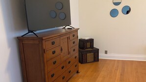 Una habitación con un aparador de madera, un televisor de pantalla plana grande y un mueble pequeño de madera.