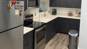 Una cocina moderna con armarios de madera oscura, electrodomésticos de acero inoxidable y encimera blanca.