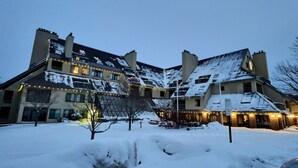 A hotel with multiple floors, snow-covered roofs, and exterior lighting. - The Grizz- AC, Pool, Sauna, Gym, Near Resort (Killington)