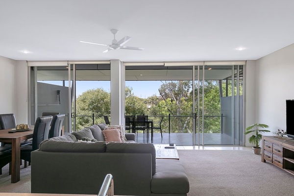 Floor-to-ceiling glass doors maximise natural light and leafy views, opening from the living area to offer a seamless connection to the outdoor dining space.