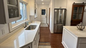 A modern kitchen with white cabinetry, stainless steel appliances, and a marble countertop. - Spacious 5BR • Walk to Main St (Cheboygan)