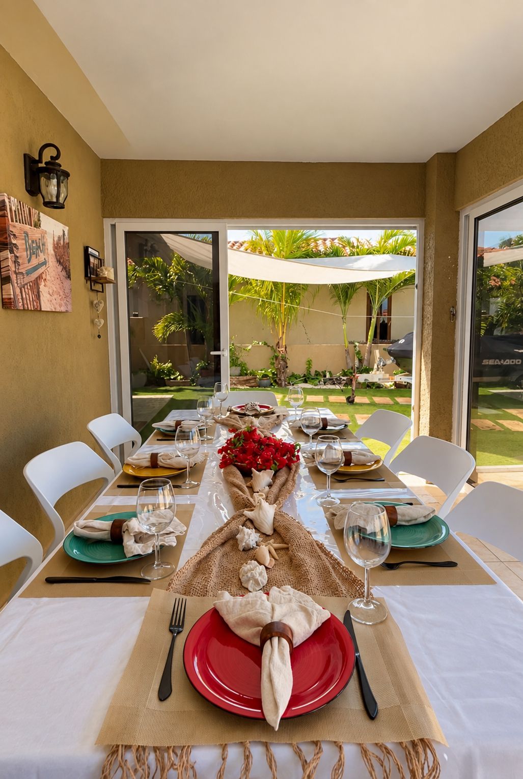 Une table à manger, avec des chaises blanches, une assiette rouge et une bouteille de vin.