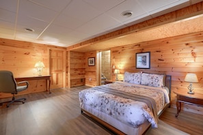A wooden-paneled bedroom with a bed, desk, and two lamps.