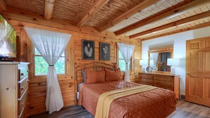 A wooden cabin bedroom with a bed, dresser, and curtains. - Cozy Casa Carezza Log Cabin, Logan, Ohio, Pet Friendly, Sleeps 6 (Logan)