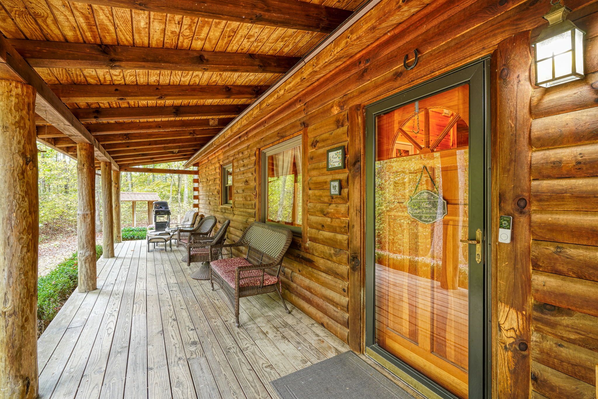 A wooden cabin with a covered porch, outdoor seating, and a door with a glass panel.
