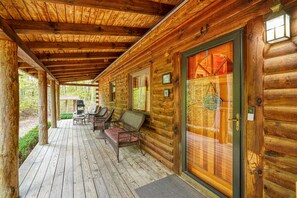 A wooden cabin with a covered porch, outdoor seating, and a door with a glass panel. - Casa Carezza, Pet Friendly (Logan)