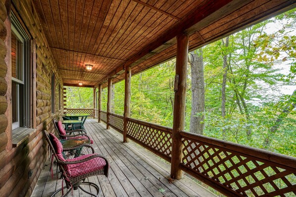 A wooden porch with a lattice railing, wicker chairs, and a table.