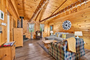 A cozy cabin interior with a wooden interior, a large clock, and a fireplace.