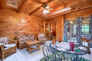 A wooden interior with wicker furniture, a ceiling fan, and a glass table with playing cards. - Casa Carezza, Pet Friendly (Logan)