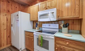A kitchen with wooden cabinets, a refrigerator, a microwave, a stove, and a sink. - Casa Carezza, Pet Friendly (Logan)