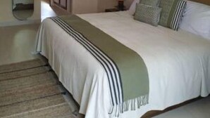 Een slaapkamer met een bed, plafondventilator, spiegel en raam.