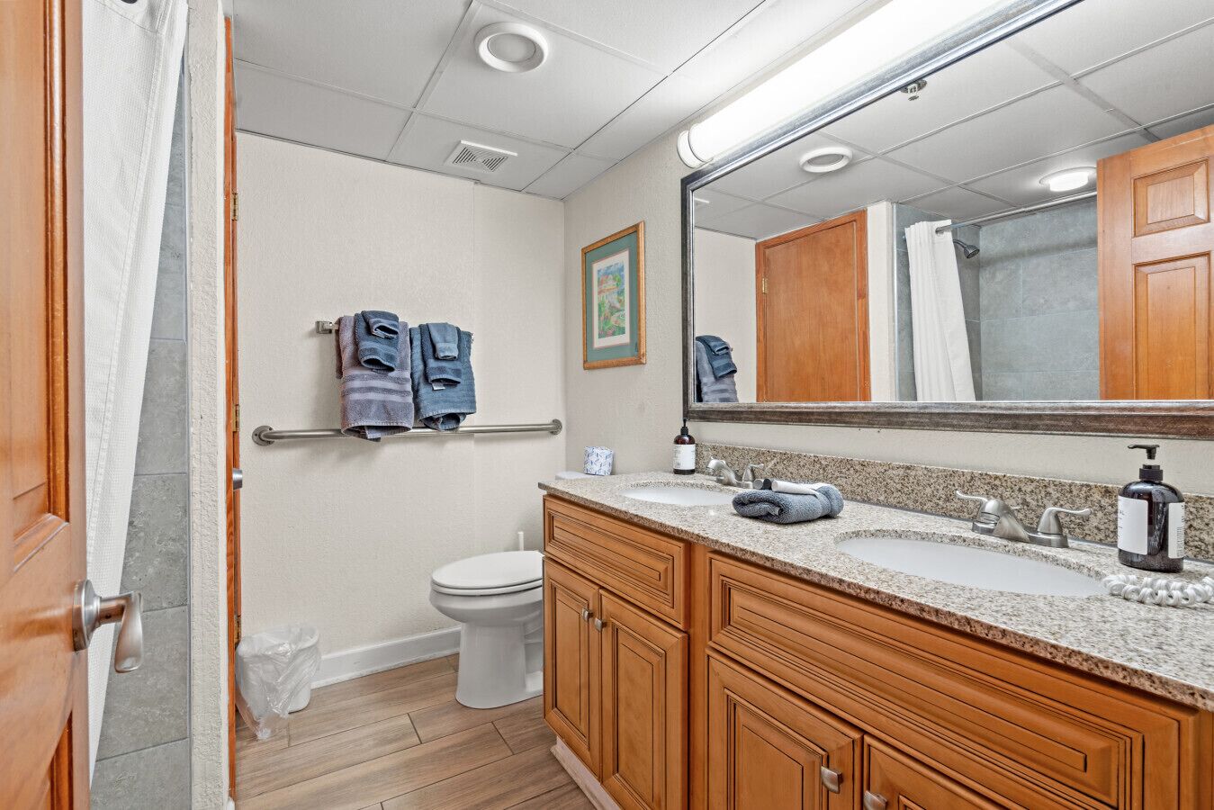A bathroom with wooden cabinets, a sink, a toilet, and a towel rack with towels.