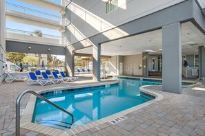Ein Poolbereich mit Liegestühlen, ein Pool mit einer 3 FT-Tiefenmarkierung und ein überdachter Gang.
