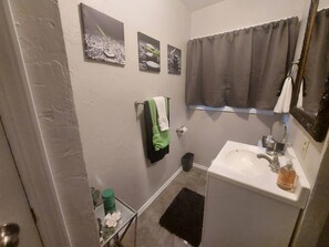A bathroom with a white sink, a mirror, a green towel, and two framed pictures on the wall. - Cheerful 3 bedroom house. Great location near Broadmoor and the Cheyenne Mt. Zoo (Colorado Springs)