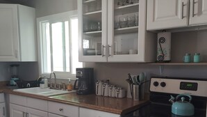 A kitchen with white cabinets, a coffee maker, a kettle, and a digital clock displaying 6:08.