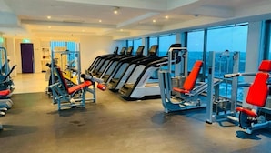 Un gimnasio con cintas de correr, máquinas de pesas y un amplio ventanal con vista al mar.