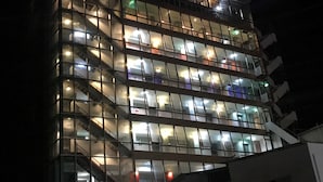Un hotel de varios pisos con fachada de vidrio moderna y ventanas iluminadas.