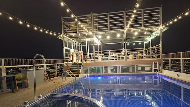 Zona de piscina con cerramiento de vidrio y terraza con sillas y mesas.