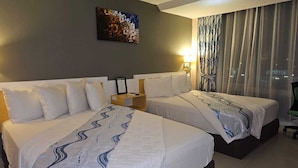 Habitación de hotel con dos camas, una mesita de noche, una lámpara, un cuadro en la pared y una ventana con cortinas.
