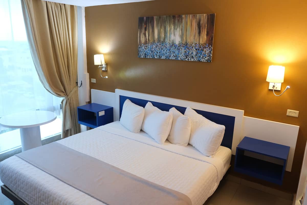 Ein Hotelzimmer mit einem großen Bett, zwei Nachttischen, einem Wandbild und zwei Wandleuchten.