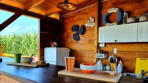 A rustic kitchen with wooden walls, a wooden countertop, and a view of tall grass outside. - Ivana Houses Ada Bojana (Ulcinj)