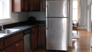 Una cocina con armarios de madera, un refrigerador de acero inoxidable y piso de madera.