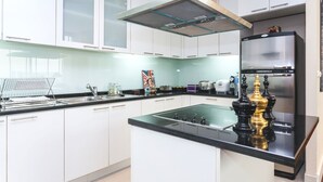 Una cocina moderna con armarios blancos, encimera negra, campana extractora de acero inoxidable y refrigerador.