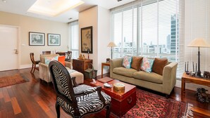 Un salón espacioso con un ventanal grande, un sofá, una mesa de centro y una silla con estampado de cebra.