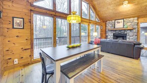 A wooden interior with a dining table, bench, and a stone fireplace. - Cozy Wisconsin Cabin w/ Deck, Kayaks & Lake Views! (Hayward)