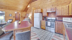 A wooden cabin with a kitchen featuring a refrigerator, stove, microwave, and wooden cabinets. - Cozy Wisconsin Cabin w/ Deck, Kayaks & Lake Views! (Hayward)