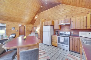 Une cabane en bois dotée d’une cuisine équipée d’un réfrigérateur, d’une cuisinière, d’un four à micro-ondes et de meubles de rangement en bois.