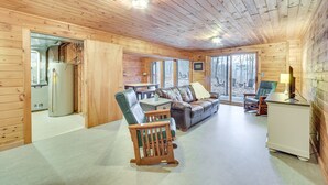 A cozy cabin interior with a wooden ceiling, a sofa, a rocking chair, a dining table, and a refrigerator. - Cozy Wisconsin Cabin w/ Deck, Kayaks & Lake Views! (Hayward)