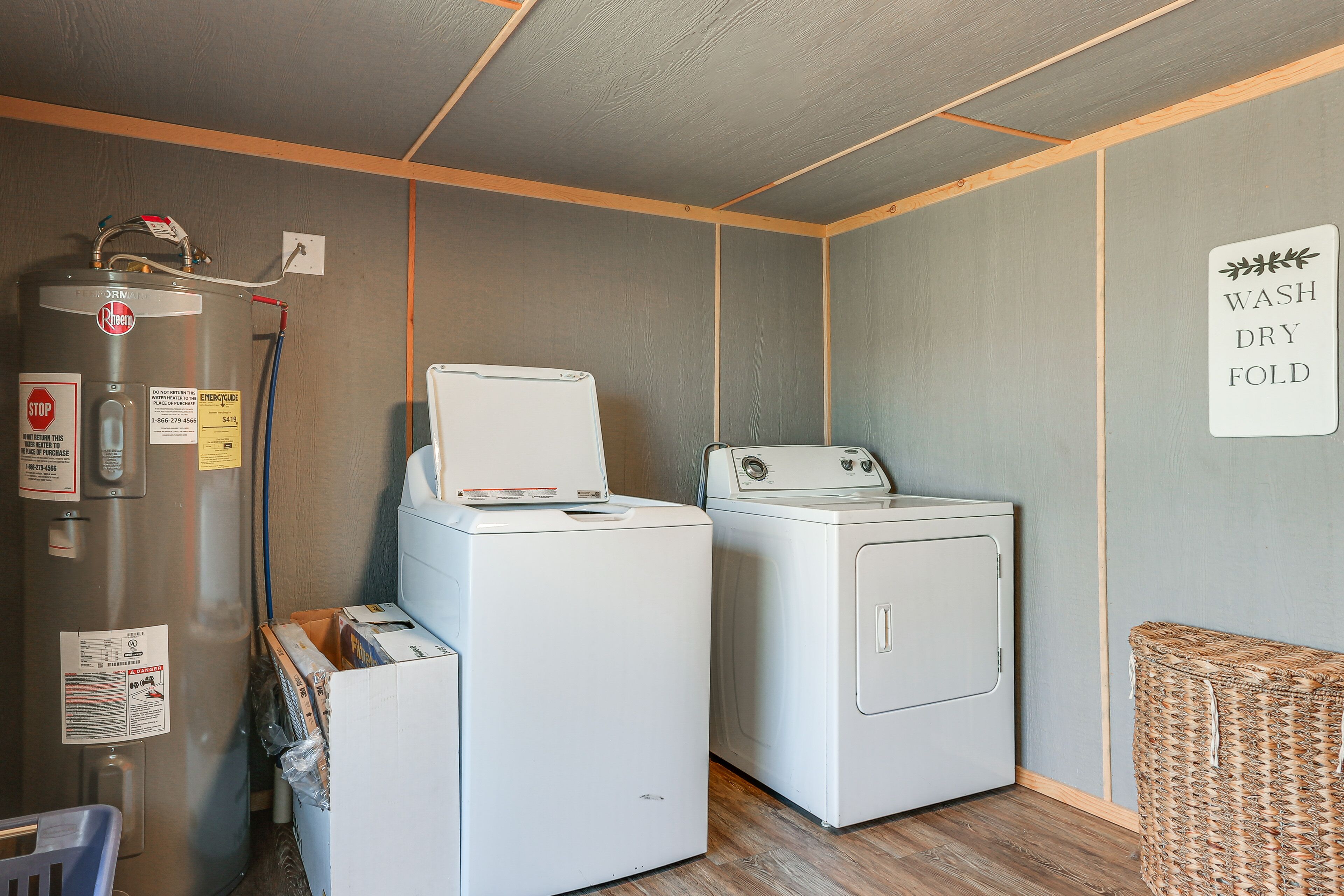 A laundry area with two white washing machines, a water heater, and a sign that says 'WASH DRY FOLD'.