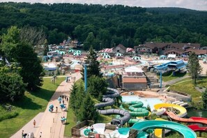 Um parque aquático com várias piscinas e toboáguas, cercado por edifícios e árvores.