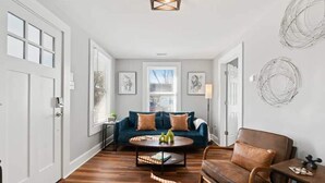 Een woonkamer met een blauwe bank, een bruine leren fauteuil en een salontafel met decoratieve objecten.